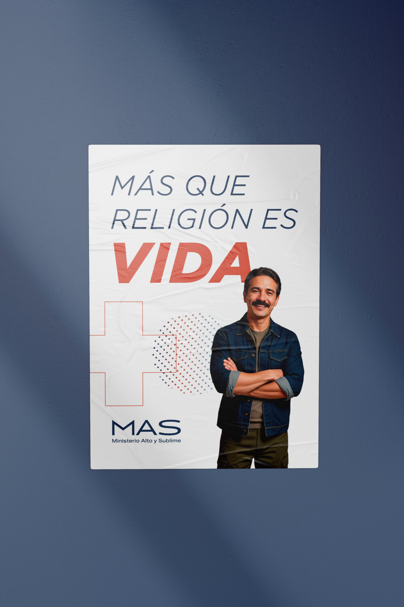 Brand application mockup: a white poster reading “Más que religión es vida” with the MAS lockup, plus symbol and halftone circle, shown against a blue wall.