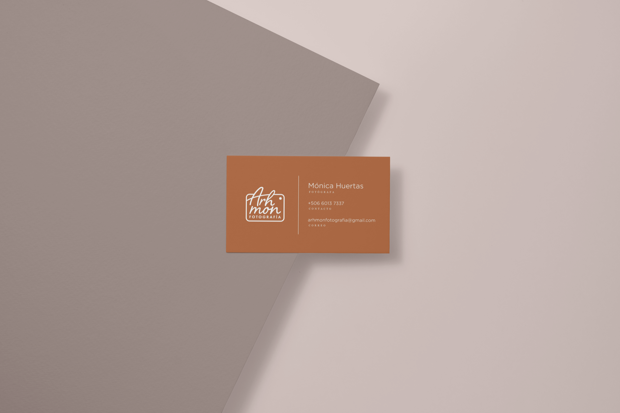 Intended application mockup: a terracotta business card on layered neutral paper showing the Arhmon Fotografía mark beside client contact details that will be removed before publication.
