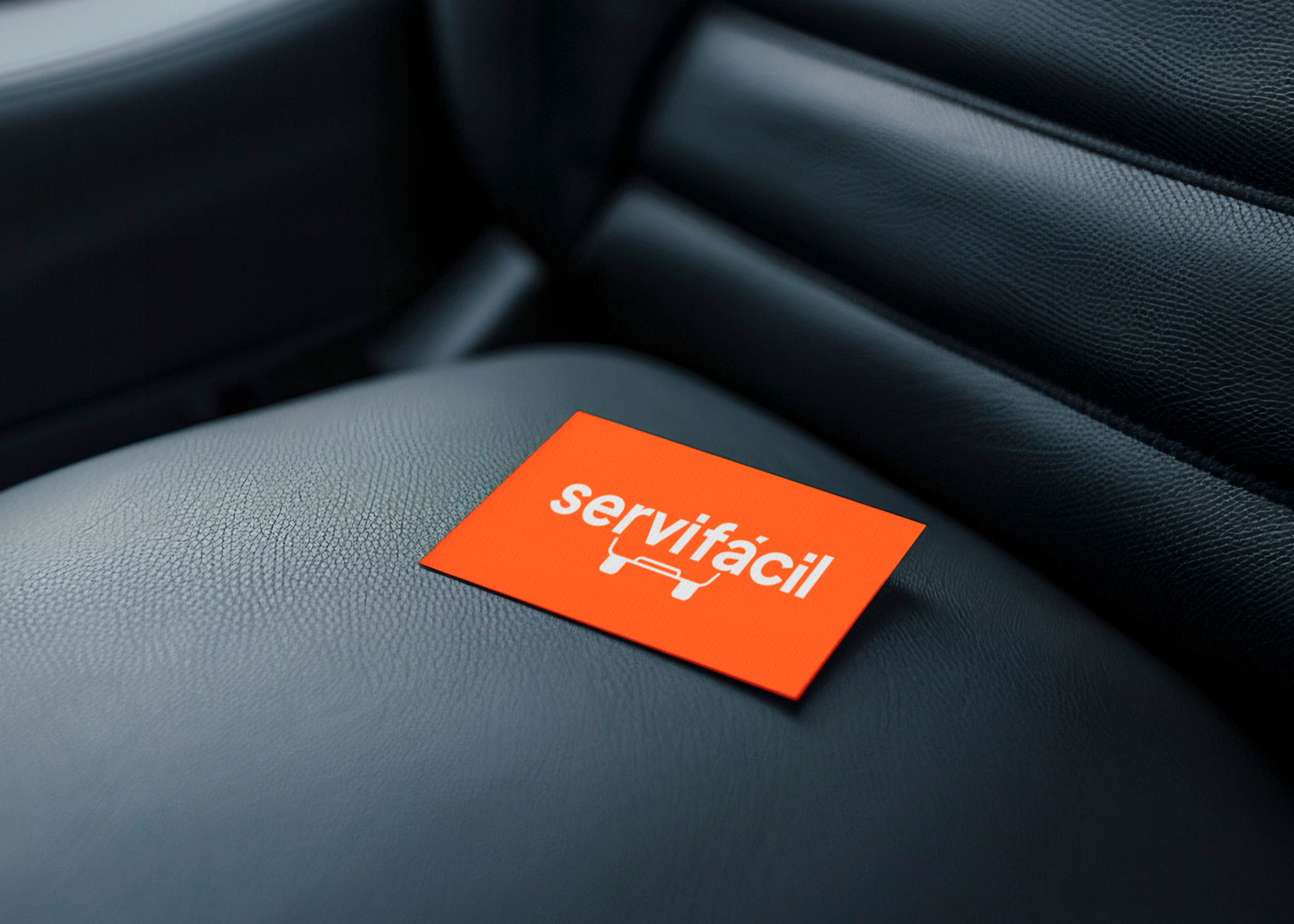 Application mockup: an orange ServiFácil card with the wordmark and car-silhouette symbol resting on a dark leather car seat.